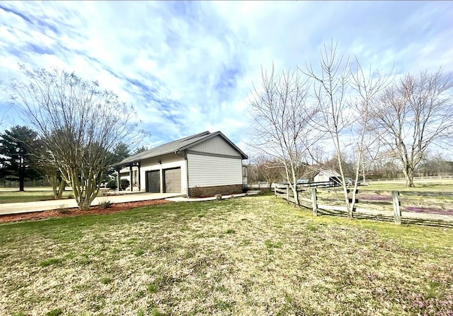 exterior space featuring fence, an outdoor structure, a yard, and an attached garage