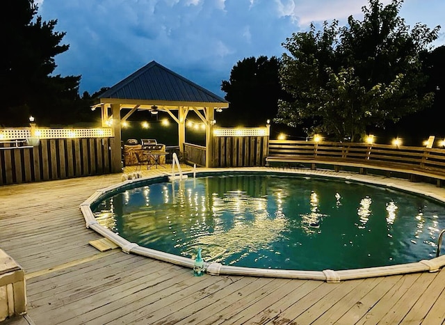 pool with a gazebo, a wooden deck, and a fenced backyard