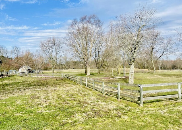 view of yard with fence and a rural view