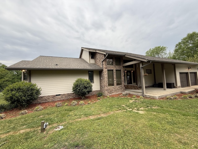 rear view of house featuring a garage and a lawn