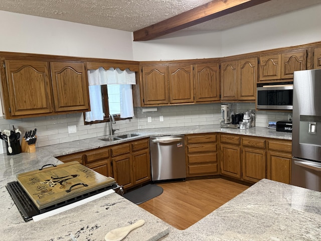 kitchen with tasteful backsplash, stainless steel appliances, brown cabinetry, and a sink
