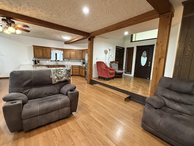living room featuring ceiling fan, light wood-type flooring, recessed lighting, and beamed ceiling
