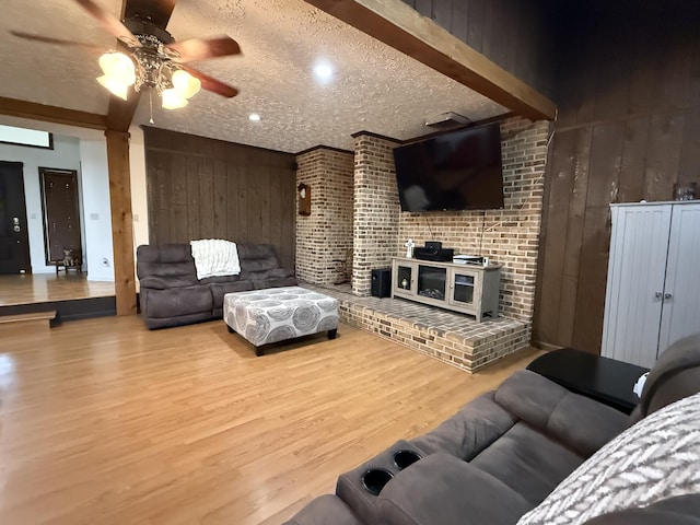 living area with wood walls, wood finished floors, ceiling fan, and a textured ceiling