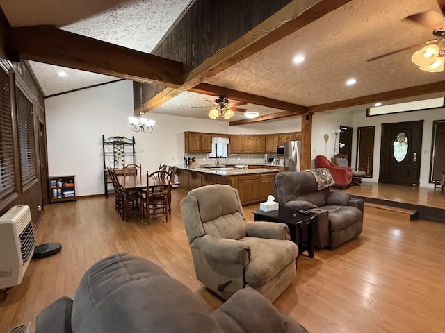 living room with beam ceiling, ceiling fan with notable chandelier, light wood-style floors, and a textured ceiling