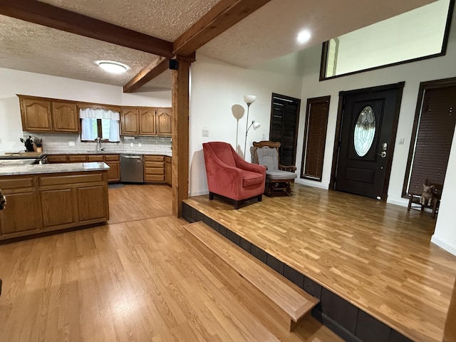 kitchen with beamed ceiling, light countertops, dishwasher, and light wood-type flooring