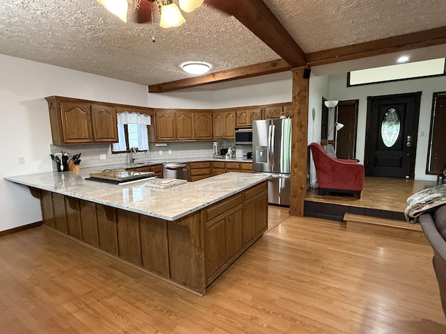 kitchen featuring a textured ceiling, a peninsula, appliances with stainless steel finishes, and light wood finished floors