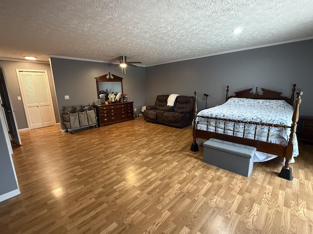 bedroom with a textured ceiling, wood finished floors, crown molding, and baseboards
