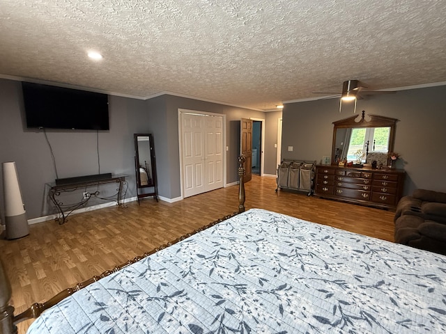 bedroom featuring ornamental molding, a textured ceiling, wood finished floors, and baseboards