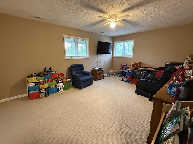 rec room with a textured ceiling, visible vents, a ceiling fan, and carpet flooring