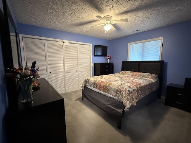 bedroom featuring a textured ceiling, visible vents, ceiling fan, a closet, and carpet