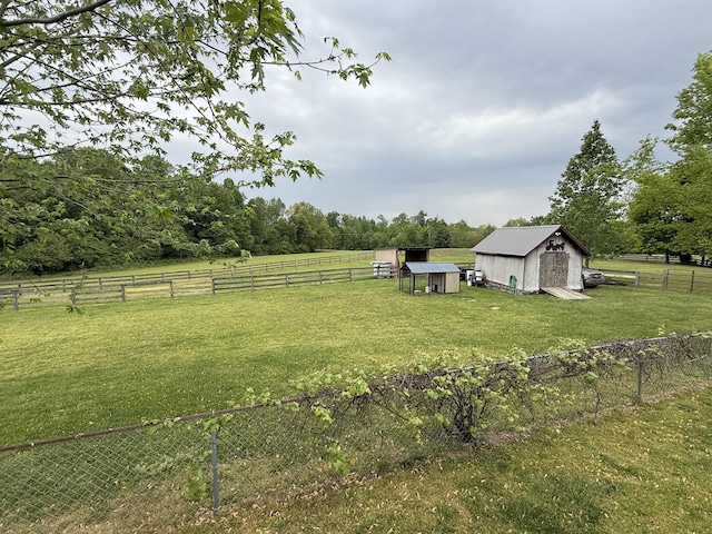 view of yard with a storage unit, a rural view, an outbuilding, fence, and exterior structure