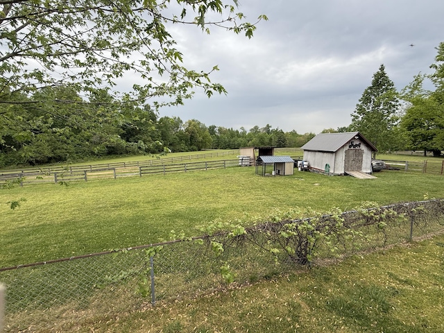 view of yard featuring a rural view, fence, an outdoor structure, and a storage shed