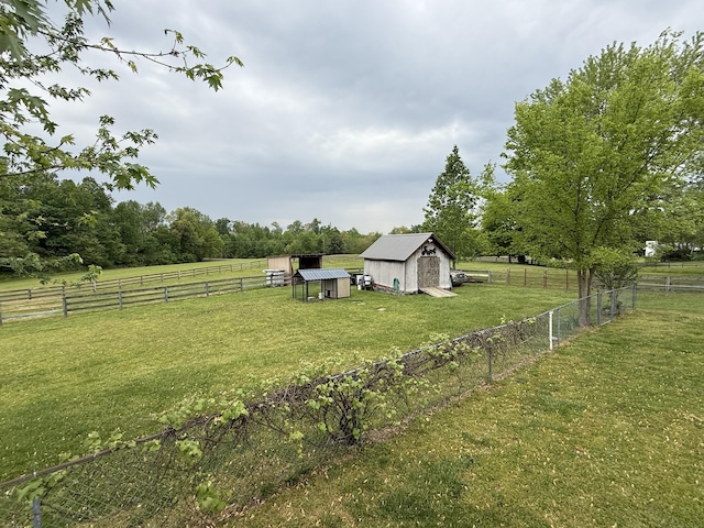 view of yard with an outbuilding, a storage shed, a rural view, and fence