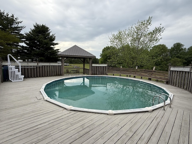 view of swimming pool featuring a gazebo, a wooden deck, a fenced backyard, and a fenced in pool