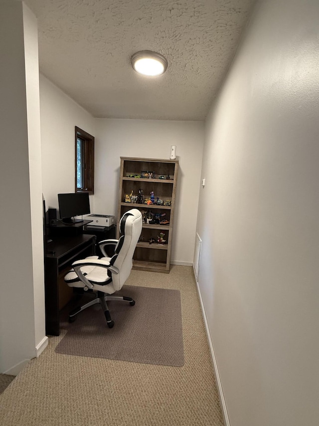 office space featuring baseboards, a textured ceiling, and light colored carpet