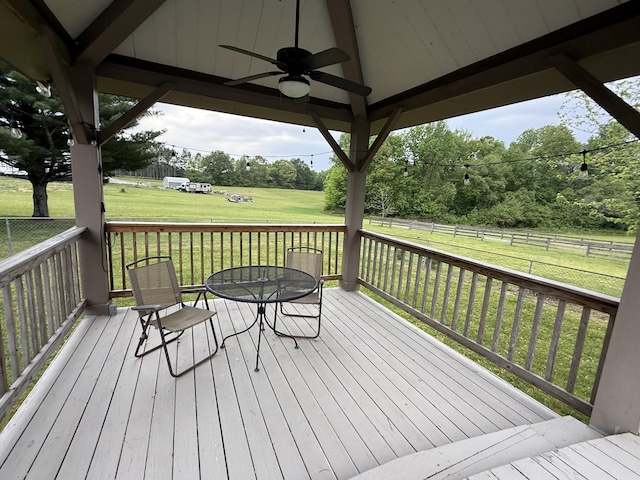 deck featuring fence, outdoor dining space, a ceiling fan, and a lawn