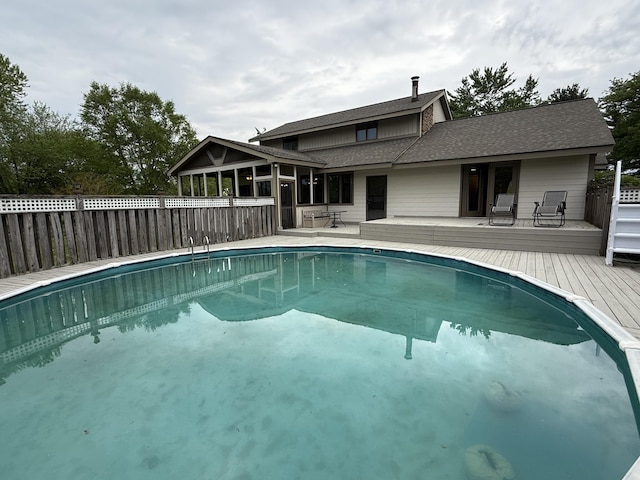 view of swimming pool with fence, a deck, a sunroom, and a fenced in pool