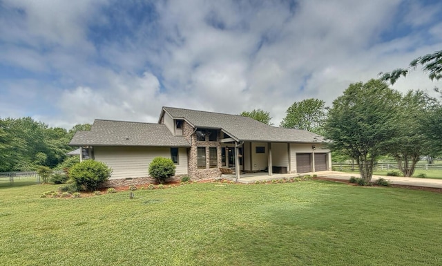 rear view of property featuring a yard, roof with shingles, concrete driveway, an attached garage, and fence