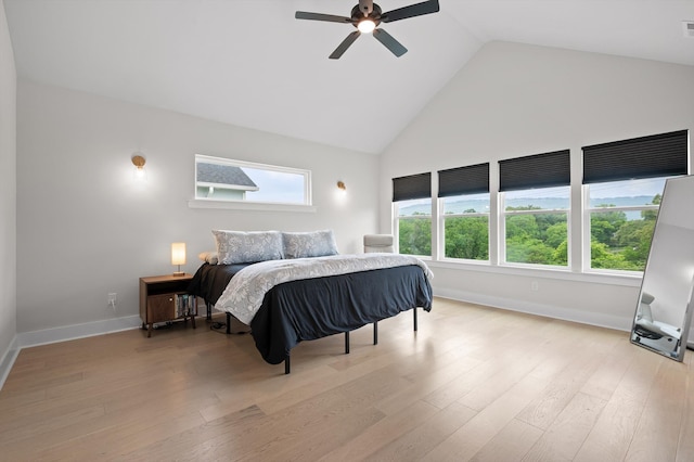 bedroom featuring light wood-style floors, high vaulted ceiling, and baseboards