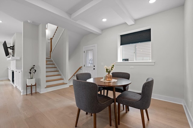 dining area featuring stairs, baseboards, beam ceiling, and light wood-style floors