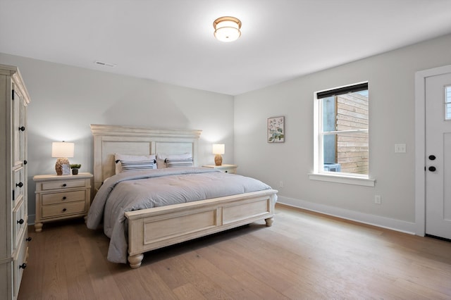 bedroom featuring baseboards, wood finished floors, and visible vents
