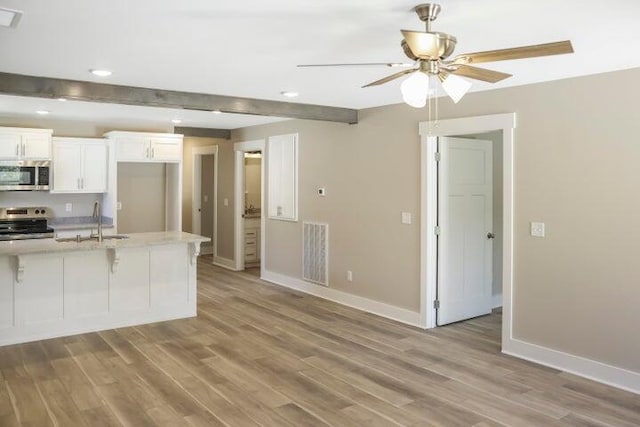 kitchen featuring a sink, light wood-type flooring, baseboards, appliances with stainless steel finishes, and visible vents