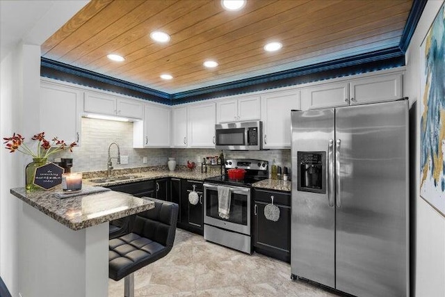 kitchen with dark stone counters, a sink, white cabinets, appliances with stainless steel finishes, and recessed lighting