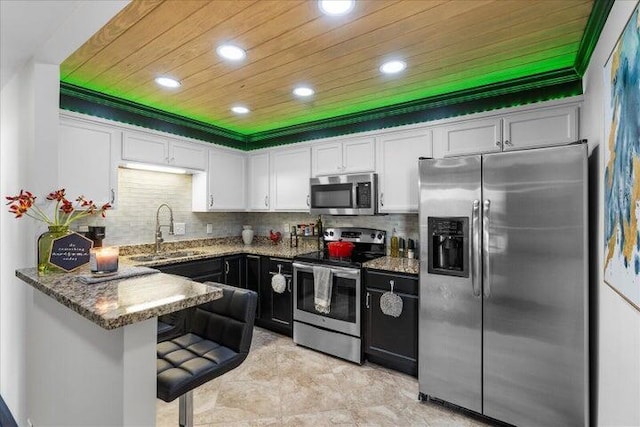 kitchen with recessed lighting, dark stone countertops, a sink, appliances with stainless steel finishes, and white cabinetry
