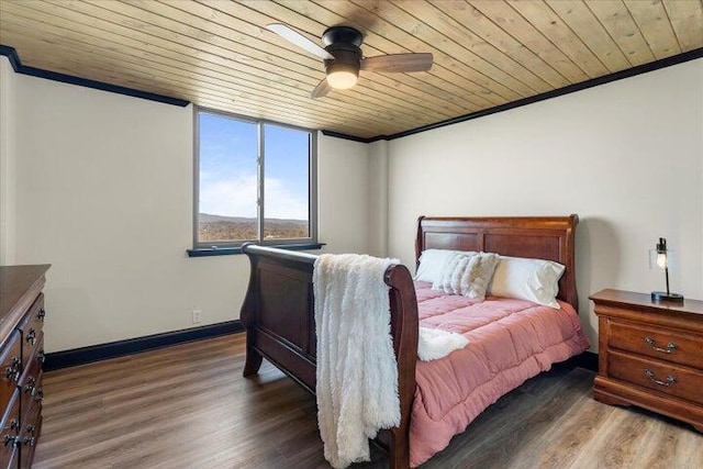 bedroom featuring wood ceiling, baseboards, wood finished floors, and crown molding