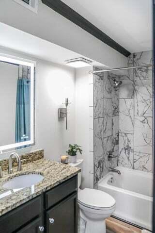 full bathroom featuring vanity, tub / shower combination, and toilet