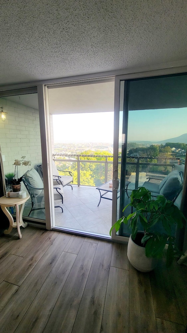 doorway featuring floor to ceiling windows, wood-type flooring, and a textured ceiling