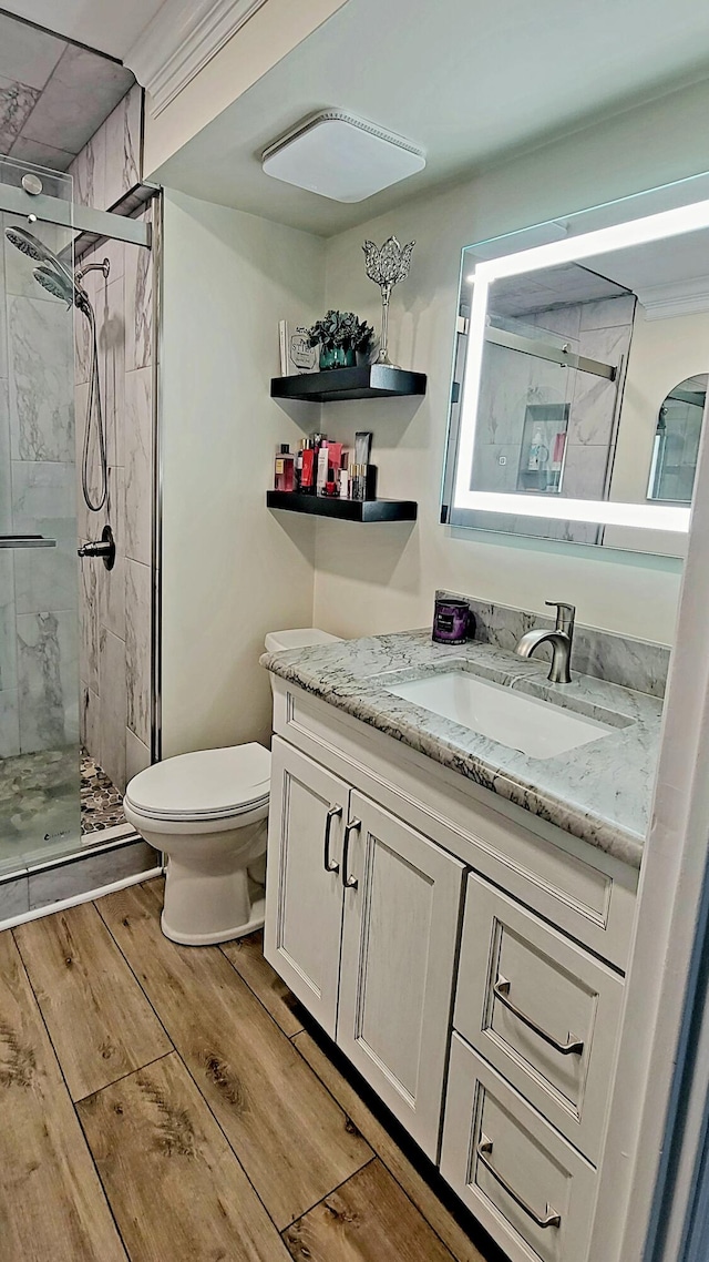 full bath featuring wood finished floors, a marble finish shower, vanity, and toilet