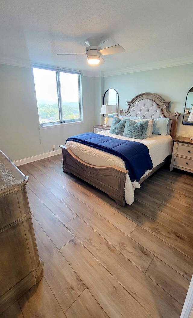bedroom with baseboards, wood finished floors, ceiling fan, and ornamental molding
