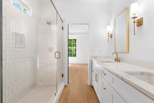 bathroom featuring a wealth of natural light, wood finished floors, a sink, and a stall shower