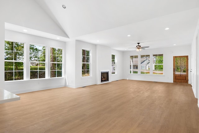 unfurnished living room with light wood-style flooring, vaulted ceiling, baseboards, recessed lighting, and a fireplace