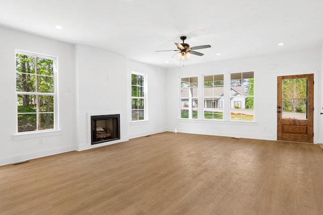 unfurnished living room featuring baseboards, visible vents, wood finished floors, ceiling fan, and a fireplace
