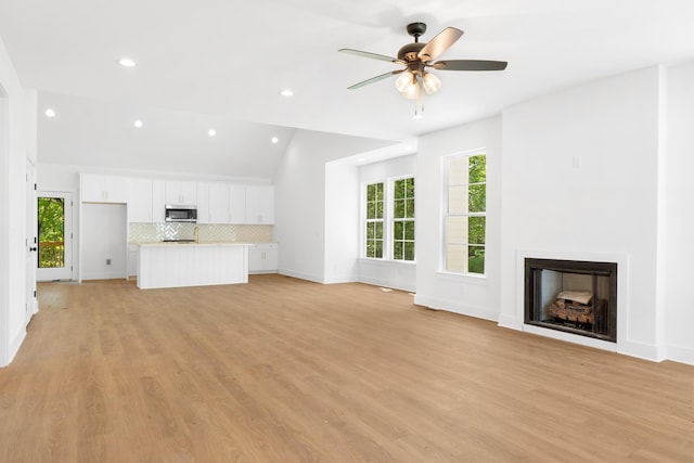 unfurnished living room with vaulted ceiling, ceiling fan, a fireplace, baseboards, and recessed lighting