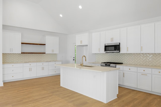 kitchen with open shelves, a sink, range, stainless steel microwave, and backsplash