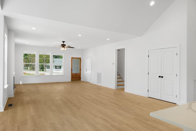 unfurnished living room with ceiling fan, stairs, light wood finished floors, and recessed lighting