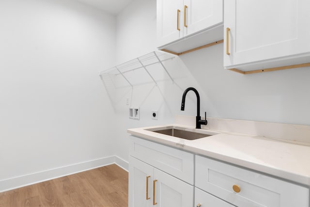 washroom featuring hookup for an electric dryer, a sink, light wood-style floors, cabinet space, and washer hookup