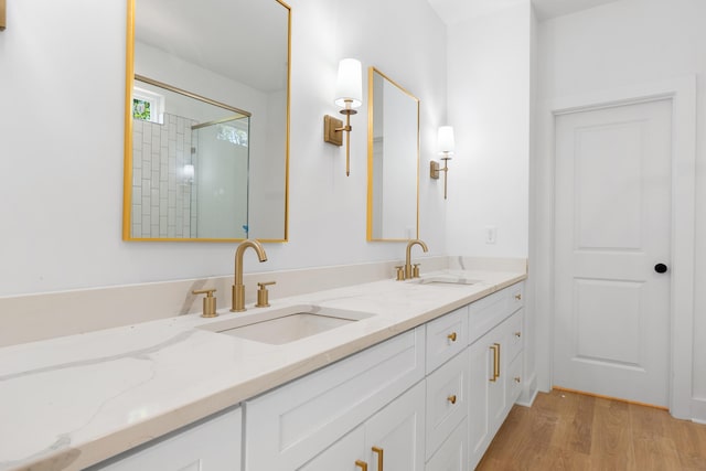 bathroom featuring double vanity, wood finished floors, a shower with door, and a sink