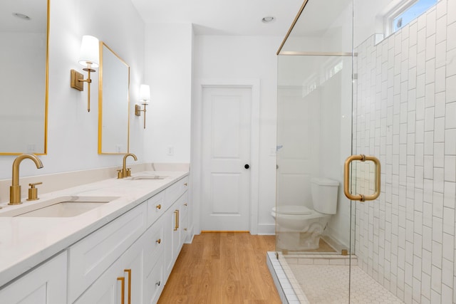 bathroom with toilet, wood finished floors, a sink, and a stall shower