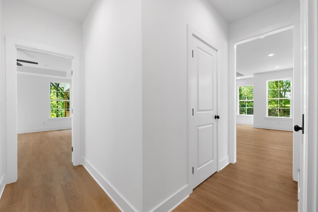 hallway with light wood-type flooring, baseboards, and recessed lighting