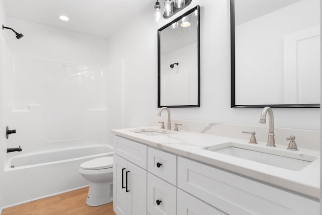 full bathroom featuring wood finished floors, a sink, double vanity, and toilet