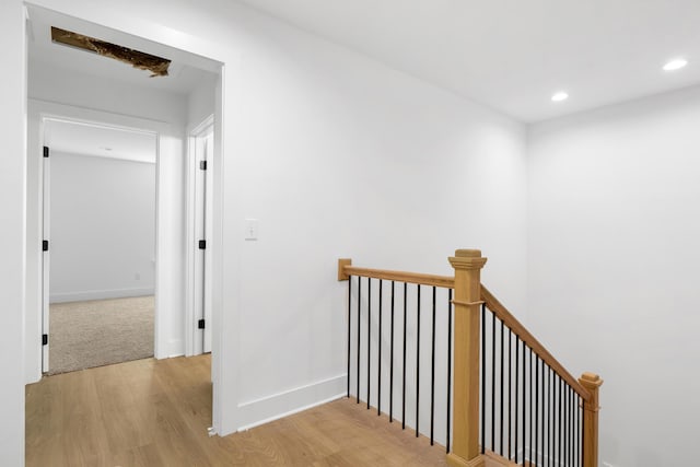 hall with recessed lighting, light wood-style floors, baseboards, and an upstairs landing