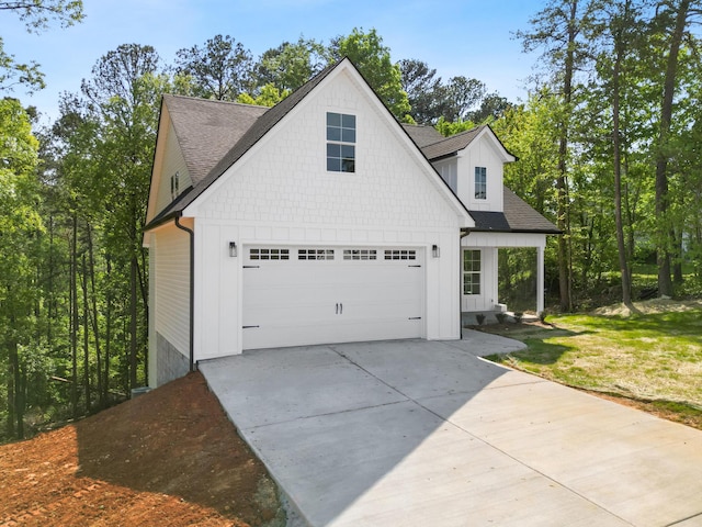 view of side of property featuring driveway, board and batten siding, and a shingled roof