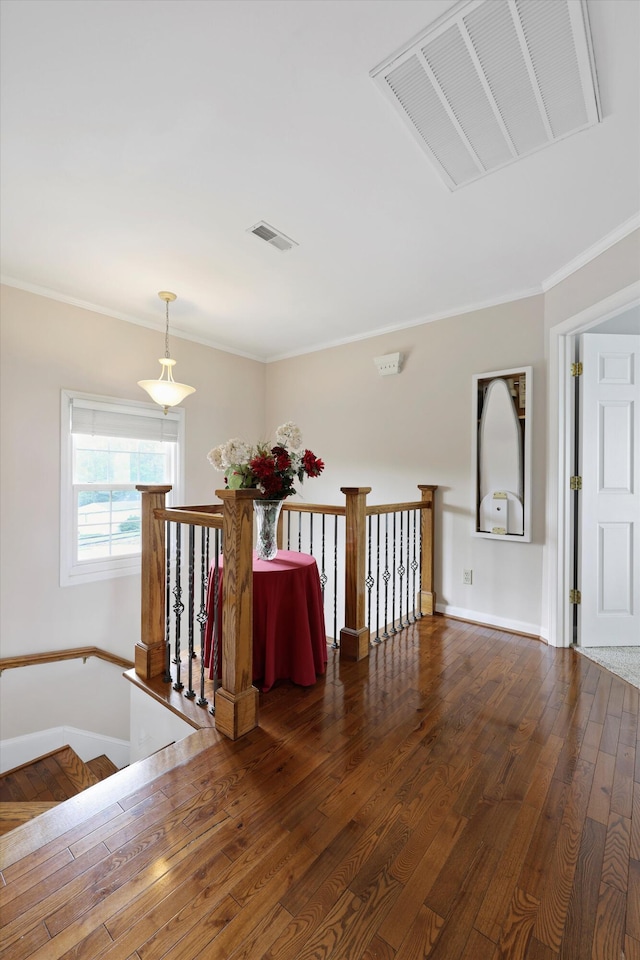 interior space featuring baseboards, hardwood / wood-style flooring, visible vents, and ornamental molding