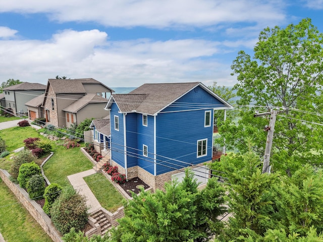 view of property exterior with stairway, roof with shingles, and a yard