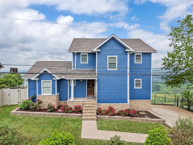 view of front of property with stone siding, a shingled roof, a front lawn, and a gate