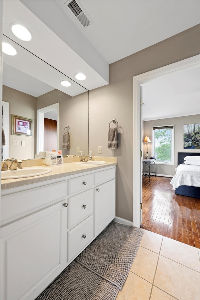 ensuite bathroom featuring tile patterned flooring, visible vents, a sink, and double vanity